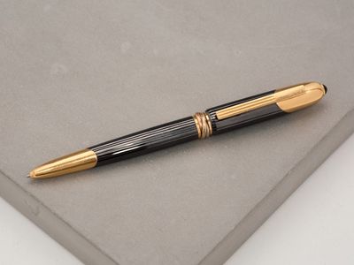 a black and gold pen sitting on top of a piece of paper
