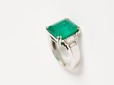 a close up of a ring with a green stone on a white surface