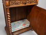 un petit meuble en bois sur lequel est posé un coussin à motifs floraux