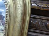a gold framed mirror sitting on top of a dresser