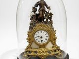 a clock under a glass dome with a statue on it