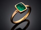 a close up of a gold ring with an emerald stone