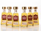 four bottles of tequila are lined up on a white surface