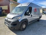 une camionnette argentée garée sur un parking à côté d'un immeuble