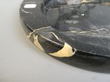 a black marble plate with a gold leaf on it