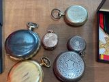 many different types of pocket watches sitting on a table