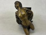bronze statue of a woman sitting on a chair next to a vase