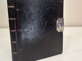 an old black book with a lock on it sitting on a table