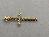 un petit pendentif en forme de croix en or sur un fond gris