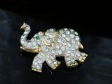 a gold and diamond elephant brooch on a black surface