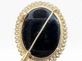 a close up of a black stone broochle on a white background