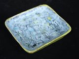 une assiette jaune et bleue posée sur une surface noire