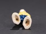 a small blue and yellow vase sitting on a black surface