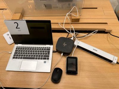a laptop, mouse, cell phone, and other electronic devices on a table