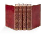 trois livres en cuir rouge sont empilés les uns sur les autres sur une surface blanche