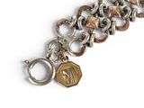 silver and gold bracelet with a coin charm on a white background