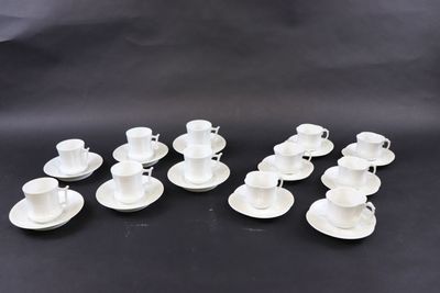 six tasses à café blanches avec leurs soucoupes, posées sur une surface noire