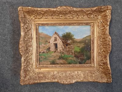 tableau représentant une vieille ferme, dans un cadre doré, posé sur un tapis bleu