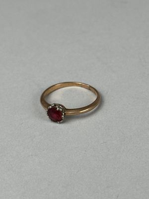 a close up of a gold ring with a red stone on it