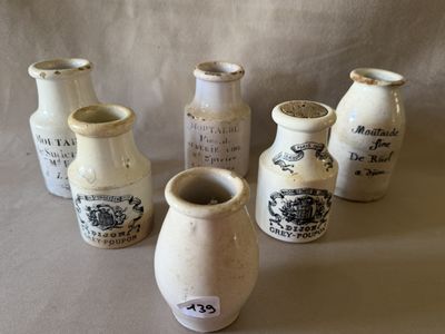 plusieurs vases blancs portant des inscriptions noires, posés sur une table