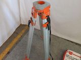 an orange and gray tripod sitting on top of a cement floor next to a bag of cement