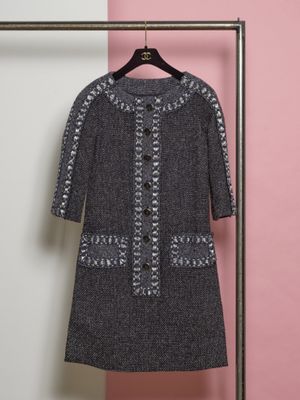 une robe noire et blanche suspendue à un cintre devant un mur rose