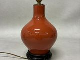 a red vase with a bird on top of it