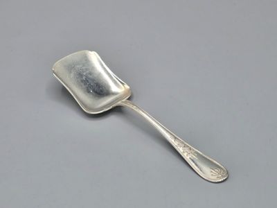 an old silver spoon with a handle on a gray surface