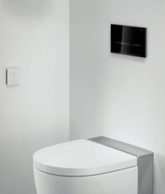 des toilettes blanches dans une salle de bains où une télévision est fixée au mur