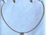 Collier plaqué or avec trois breloques sur fond blanc