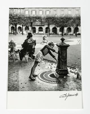 a black and white photo of two children playing with a fire hydrant