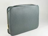 grey leather laptop case with gold zipper on white surface