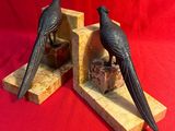 paire de serre-livres représentant des oiseaux noirs sur un socle en marbre, sur fond rouge