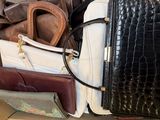 une boîte remplie de sacs à main et autres sacs posée par terre