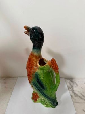 un oiseau en céramique au bec vert et orange
