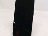 a black cell phone sitting on a stand on a table