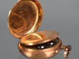 a close up of a gold pocket watch on a reflective surface