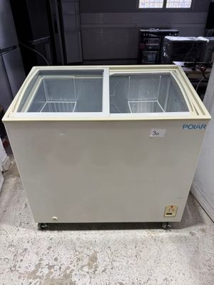 a white chest freezer sitting on top of a floor next to a wall