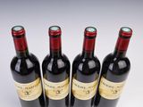 four bottles of wine are lined up in a row on a white surface