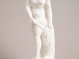 white marble statue of a woman holding a bag