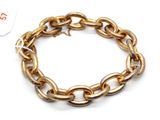 gros plan d'un bracelet en chaîne en or sur fond blanc