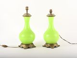 une paire de lampes en verre vert avec des pieds en laiton, posées sur une surface blanche