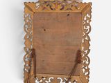 a woman standing next to a mirror with a wooden frame