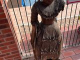 a statue of a woman that is standing next to a fence