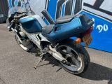 une moto bleue garée devant un mur recouvert de graffitis