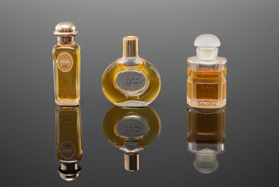 trois flacons de parfum posés les uns à côté des autres sur une surface réfléchissante