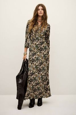 a woman in a long dress and black boots standing in front of a white wall