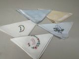 six mouchoirs ornés de monogrammes brodés, posés sur une table