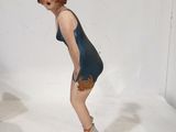 une figurine représentant une femme en maillot de bain, assise sur un rocher