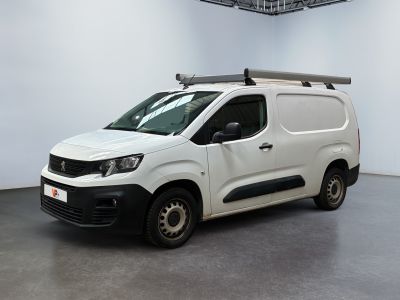 La camionnette blanche est garée dans une grande pièce équipée d'une galerie de toit.